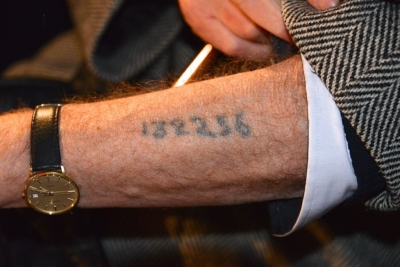 Un survivant de la Shoah montrant le numéro tatoué sur son bras par les nazis (photo : Frankie Fouganthin - Own work, CC BY-SA 3.0, https://commons.wikimedia.org/w/index.php?curid=24277501).