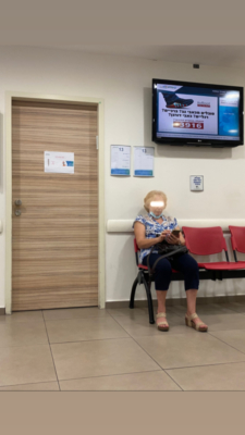 Une dame d’un certain âge attendant son tour chez le médecin. Au lieu de porter son masque sur le visage, elle le porte sur le menton. Le manque de discipline de nombreux Israéliens concernant le port du masque est flagrant (photo : KHC).